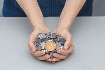 Golden Bitcoin in palms with coins. Risks, stock market fluctuations and Bitcoin cryptocurrency.