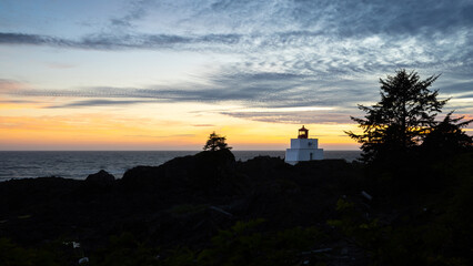 Fototapeta premium Beautiful View of the Amphitrite Point Lighthouse on the Rocky Pacific Ocean Coast during a colorful cloudy sunset. Taken on Wild Pacific Trail in Ucluelet, Vancouver Island, BC, Canada.
