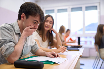 Shocked student looking at failed exam at school desk