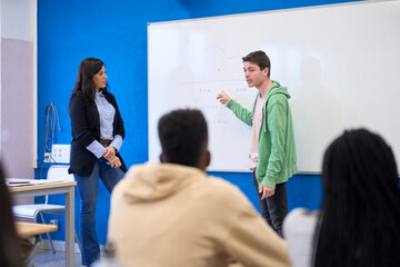 Obraz premium Institute students solving math equation on whiteboard with teacher