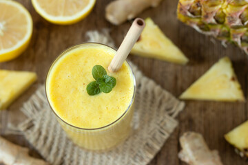 Pineapple smoothie with lemon and ginger in a glass with mint and bamboo straw. Top view. Healthy...