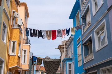 Colorful street in Balat with clothes hanging from line between two houses buildings. Washed clothes hanging and drying on ropes between residential buildings. Poor district of Istanbul