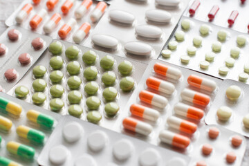 Big pharma metal tablet blister. Multicolor pills medicine. Silver shiny blister with drugs. Transparent capsules in blister pack closeup.