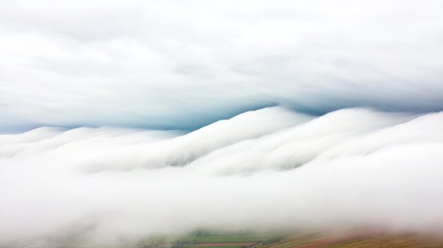 Soft, rolling clouds blanket landscape, creating serene, dreamli