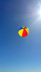 A glass beach ball with swirling colors of summer, suspended mid-air against a bright sky.