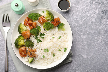 Tasty rice with broccoli and chicken served on grey table, top view. Space for text