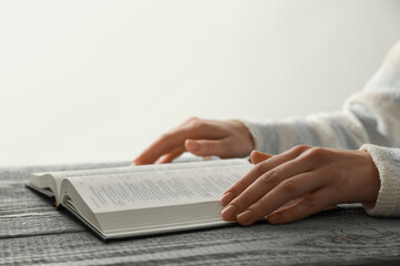 Woman with open Holy Bible in English language at wooden table, closeup