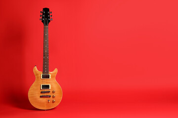 Obraz premium One modern electric guitar on red background. Space for text