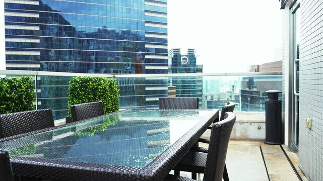 Table and chairs on balcony of highrise building in the city, slow motion video