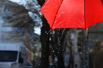 Open red umbrella under pouring rain outdoors, closeup