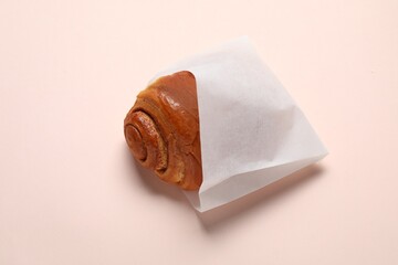 Paper bag with freshly baked bun on beige background