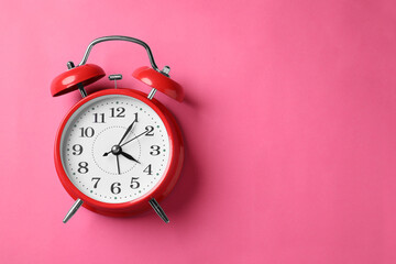 Red alarm clock on pink background, top view. Space for text