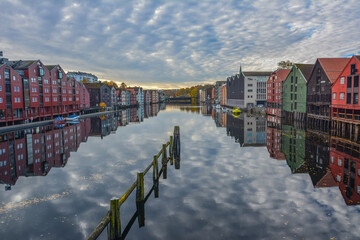 Colorful old storehouses perfectly mirroring on the Nidelva River in autumn in the city of Trondheim in Trondelag county, Norway