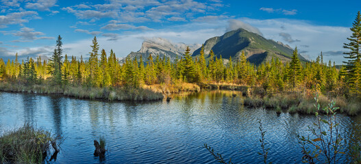A stunning view of Vermillion Lake with Mount Rundle in the background. The calm water, autumn...