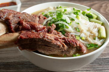 A closeup view of a bowl of pho, featuring beef back ribs.