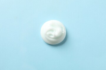 Sample of body cream on light blue background, top view