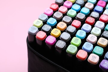 Many colorful markers in bag on pink background, closeup