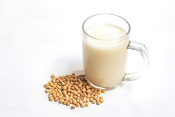 glass of soy milk and soy beans on white background