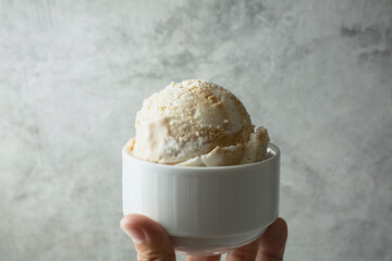 A view of a hand holding a bowl of caramel swirl ice cream.