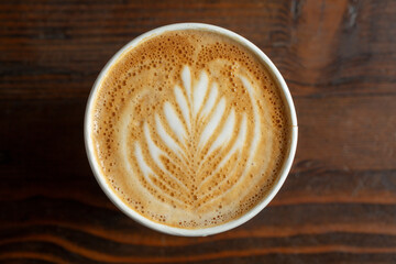 A top down view of a coffee latte drink, featuring latte art.