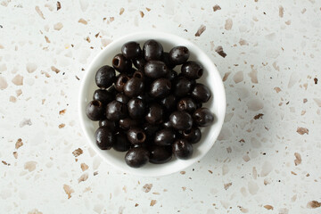 A top down view of a bowl of canned pitted black olives.