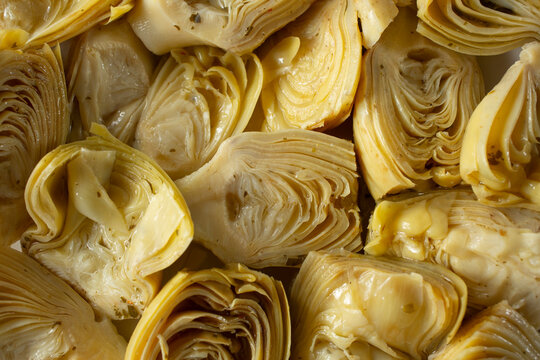 A top down view of a layer of marinated artichoke hearts, as a background.