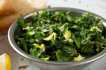 A closeup view of a small metal bowl of gremolata.