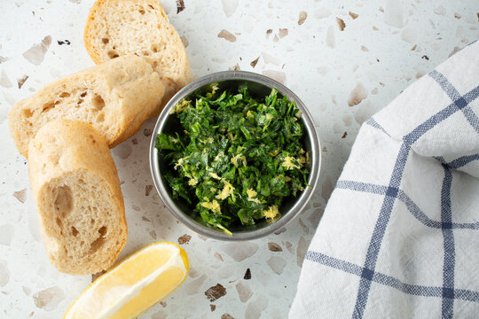 A top down view of a small metal bowl of gremolata.