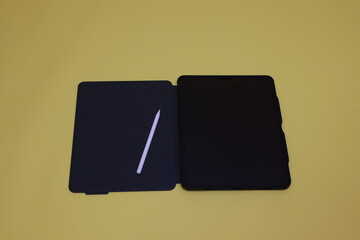 Digital tablet and digital pen with green, white, and blank screen on a yellow background.