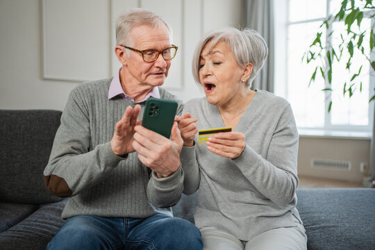 Senior couple man woman shopping online with smartphone paying with credit card. Old people buying on Internet enter credit card details at home indoors. Online shopping delivery service ecommerce - Powered by Adobe