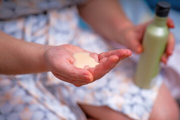woman's hand holds a thick light green pine cream extracted from a plastic bottle. The creamy...