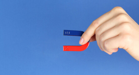 Woman with horseshoe magnet on blue background, closeup. Space for text