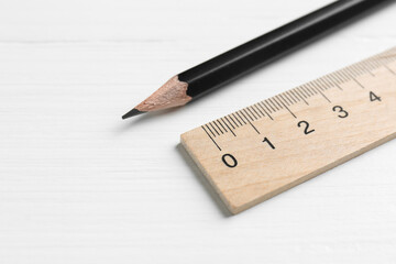 Ruler and pencil on white wooden table, closeup. Space for text