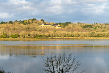 Vue sereine de l'abbaye de Land&eacute;vennec, entour&eacute;e de verdure, se refl&eacute;tant doucement dans les eaux de l'aulne, sous un ciel nuageux mais lumineux sur la presqu'&icirc;le de Crozon