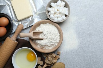 Rolling pin and ingredients for dough on light grey table, flat lay. Space for text