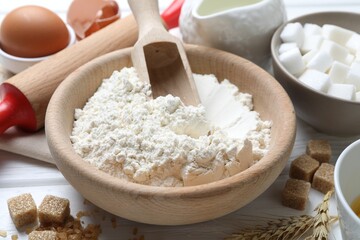 Ingredients for dough and rolling pin on white wooden table, closeup