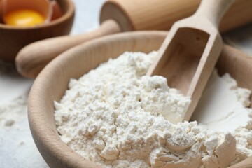 Flour in bowl, rolling pin and yolk on table, closeup