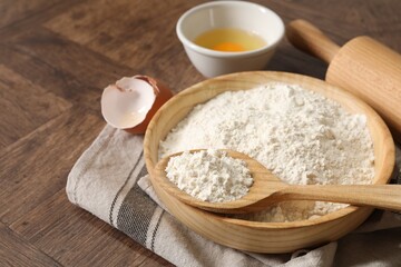 Rolling pin, flour and yolk on wooden table, closeup