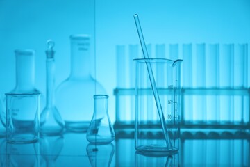Laboratory glassware on mirror surface against light blue background