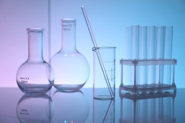 Laboratory glassware on mirror surface against color background