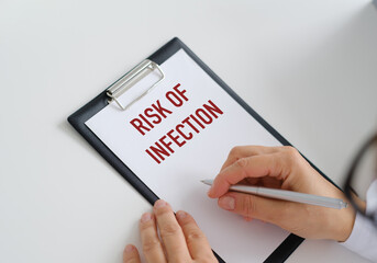 Risk of infection text written on a paper tablet in the hands of a doctor