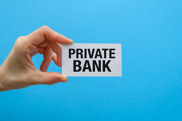A white paper card in hands on a blue background with the inscription Private Bank