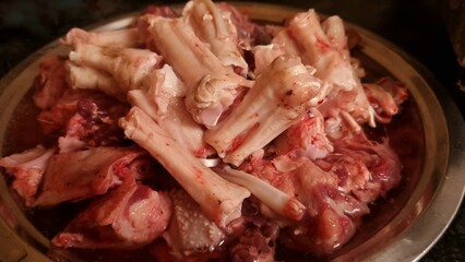 Fillets of legs meat of broiler chicken cutting in pieces by butcher and isolated in plate for cooking 