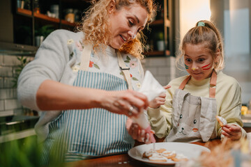Mother and daughter decorating easter cookies together in the kitchen