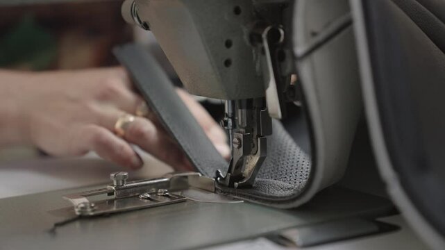 sewing master special sewing machine sews leather product. making product from fabric leather. tailor working. hands close-up. production industry concept. workshop seamstress couturier order clothes