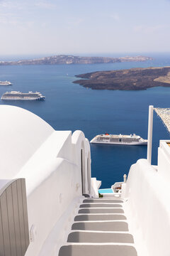 Stairs in Santorini with views of the sea and a cruise ship passing by. 