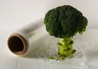A roll of cling film and broccoli on the table