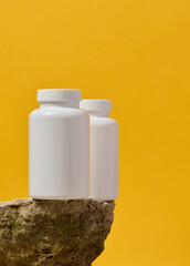 White plastic medicine jar on stone, yellow background. Mock up