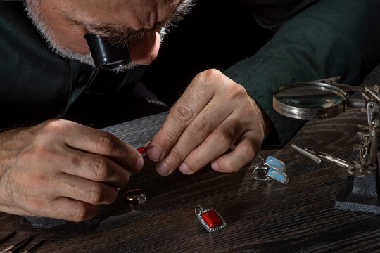 Professional goldsmith Jewelry appraiser examines and evaluating gemstones jewelry, bijouterie looking through magnifying glass monocular.
