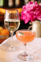 Refreshing cocktails served in elegant glassware with vibrant floral backdrop at an upscale venue in the evening